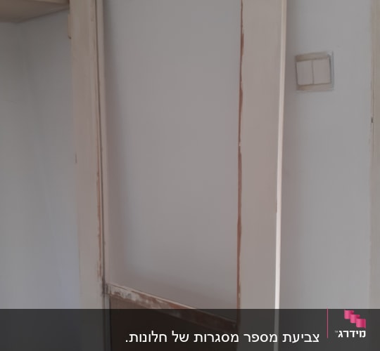 דלת עץ עם מסגרת מתקלפת, חלקית צבועה